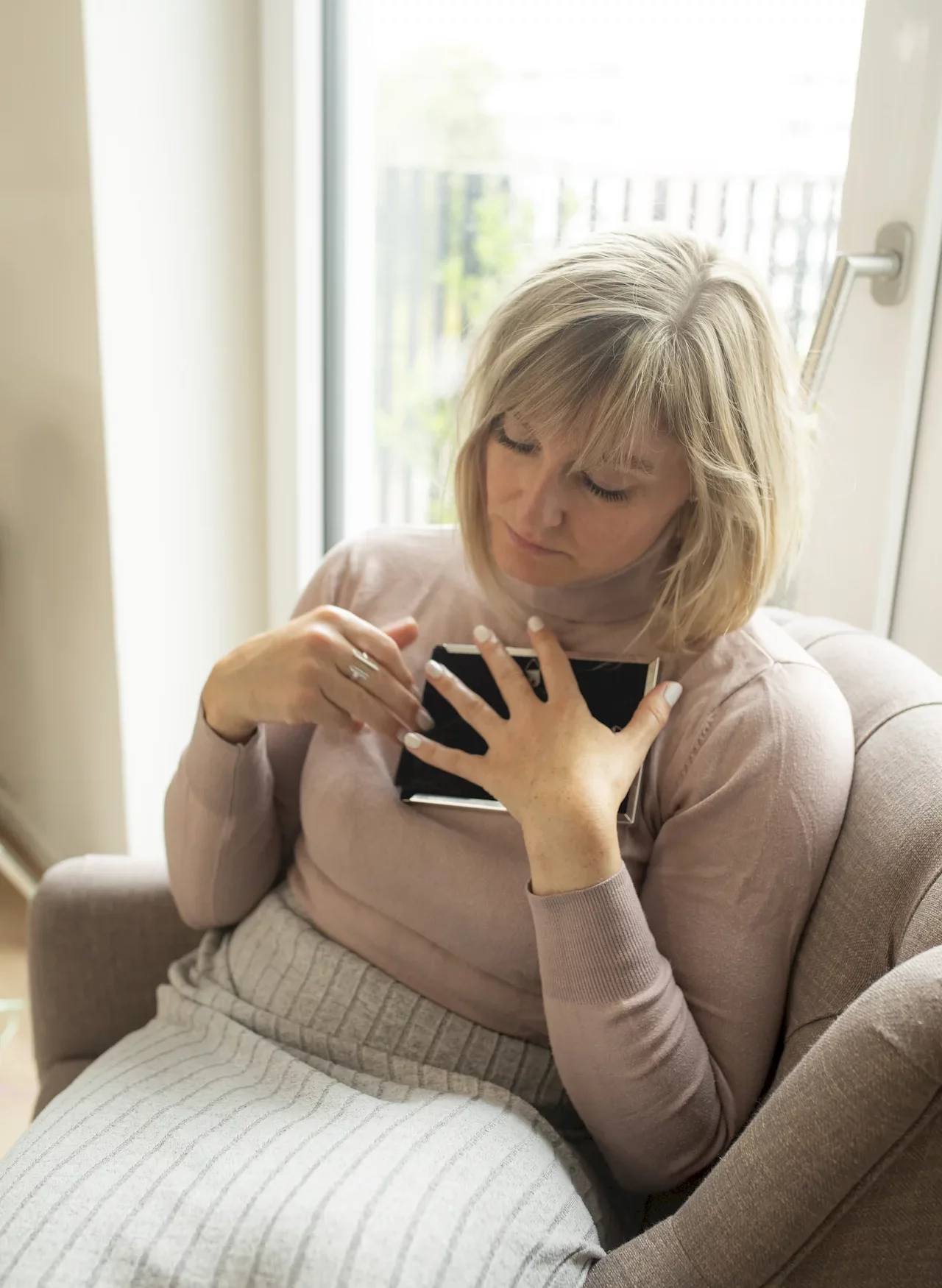 Frau sitzt nachdenklich mit einem Bild auf der Brust